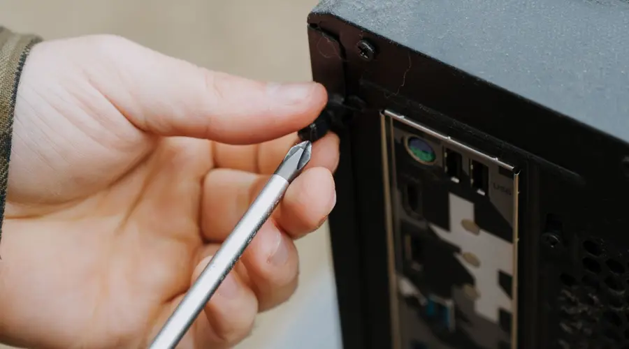 Technician servicing an open desktop gaming computer with a screwdriver