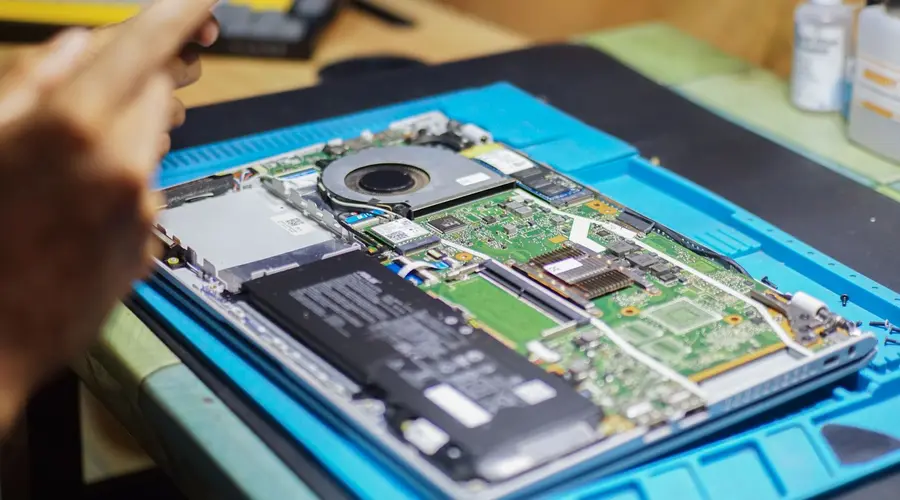 Technician repairing the internal components of an open laptop
